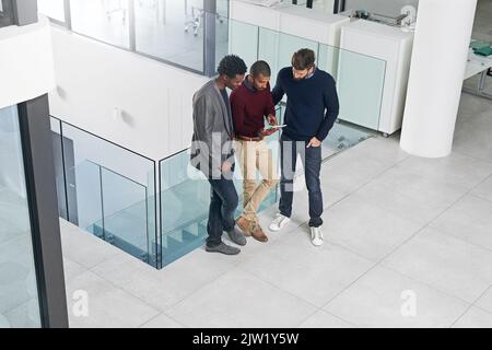 Looking for ideas online. a group of businessmen having a discussion over a digital tablet. Stock Photo