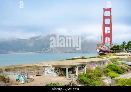 Old World War 2 concrete bunkers with graffiti in the foreground with The Golden Gate Bridge in the background in San Francisco, California, USA Stock Photo