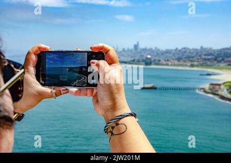 A lady framing up a photography of San Francisco on her mobile phone. Stock Photo