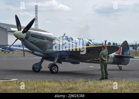 SM250 twin seat Spitfire taxiing on the runway of Solent airport while a crew member gives hand signals to the pilot. Stock Photo