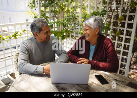 Senior african american couple sitting on terrace using laptop Stock Photo