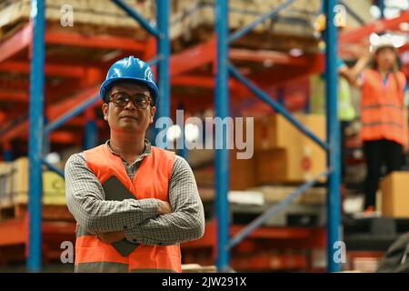 Portrait of mature male supervisor standing in warehouse with his arm crossed and looking at camera Stock Photo