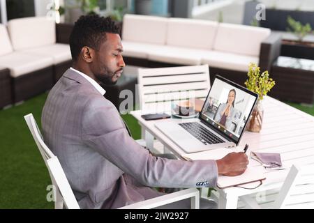 Multiracial male and female business colleagues discussing work through online meeting in office Stock Photo