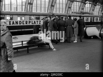 GDR, Berlin, 14. 3. 1988, drunken man on a bench at Alexanderplatz station, group of NVA soldiers Stock Photo