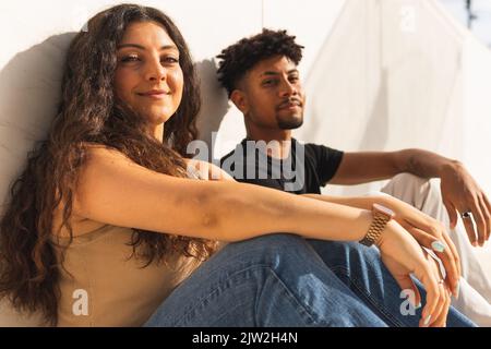Portrait of smiling confident young couple sitting by wall Stock Photo