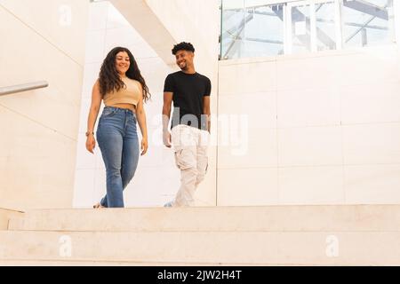Smiling young man looking at girlfriend while walking in corridor Stock Photo