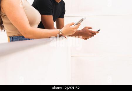Anonymous young woman and man using smartphone while standing in balcony Stock Photo