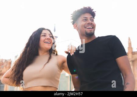 From below cheerful young couple laughing while standing in city Stock Photo
