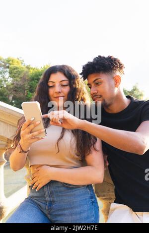 Young couple looking at smartphone while standing on steps in city Stock Photo