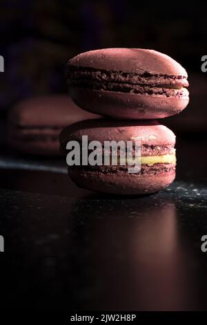 Closeup pair of delicious sweet macaroons of purple color stacked together on sunlit table in morning Stock Photo