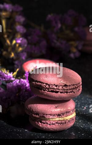 Pair of delicious sweet macaroons of purple color stacked together on sunlit table in morning Stock Photo