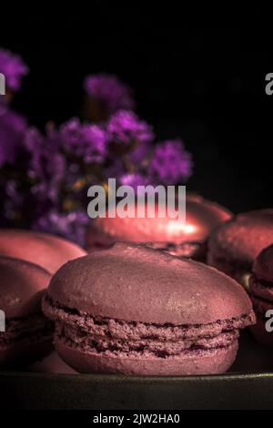 Delicious sweet macaroons of purple color together on sunlit table in morning Stock Photo