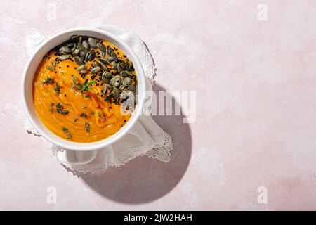 Top view of appetizing healthy pumpkin puree with seeds and seasoning served in white ceramic bowl on table in daylight Stock Photo
