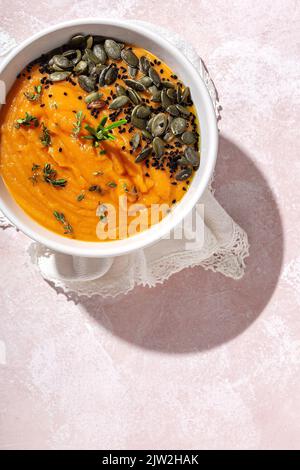 Top view of appetizing healthy pumpkin puree with seeds and seasoning served in white ceramic bowl on table in daylight Stock Photo
