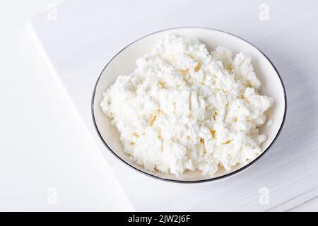 White porcelain bowl with grainy cottage cheese isolated on a white background Stock Photo