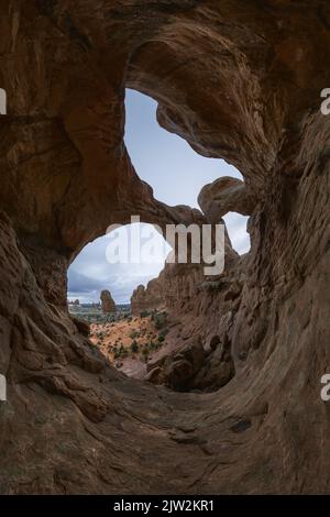 Breathtaking view of arid Arches National Park through rough Double Arch formation on overcast day in Utah, USA Stock Photo