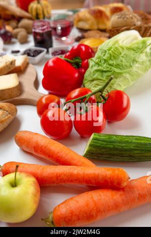 From above assorted ripe vegetables and apple placed on white table near other food Stock Photo
