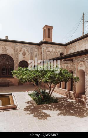 Pond against facade of medieval building with arched passages and ornamental details on street of Kashan on summer day Stock Photo