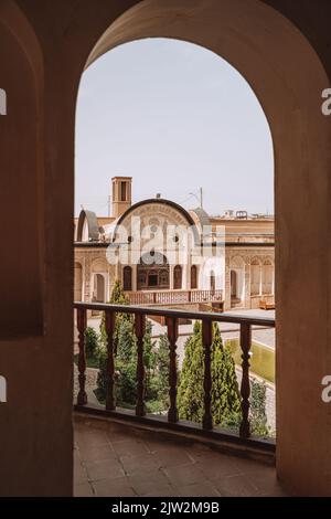 Medieval stone building with arched passage leading to balcony with fence against historic house in town on sunny summer day Stock Photo