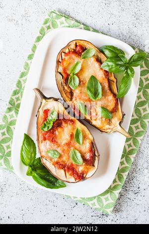 Plate with tasty baked Eggplant Parmesan and ingredients on blue ...