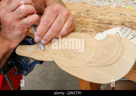 A wood carver is working on a Maori carving at the Carving school at Te Puia Maori arts and crafts Institute near Rotorua on North Island in New Zealand. Stock Photo