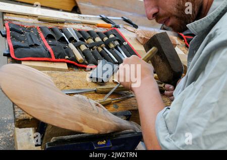 A wood carver is working on a Maori carving at the Carving school at Te Puia Maori arts and crafts Institute near Rotorua on North Island in New Zealand. Stock Photo