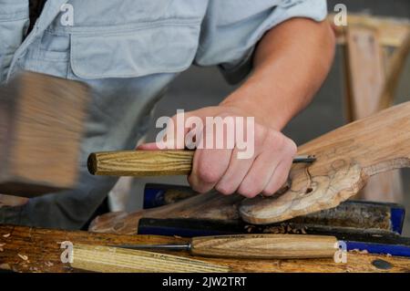 A wood carver is working on a Maori carving at the Carving school at Te Puia Maori arts and crafts Institute near Rotorua on North Island in New Zealand. Stock Photo