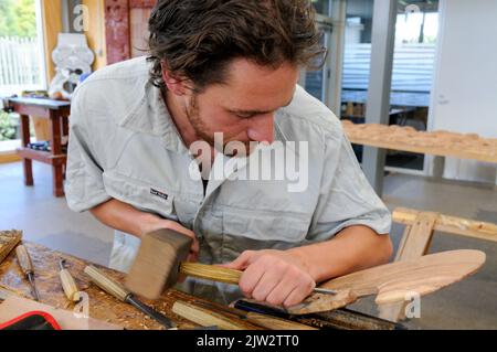 A wood carver is working on a Maori carving at the Carving school at Te Puia Maori arts and crafts Institute near Rotorua on North Island in New Zealand. Stock Photo