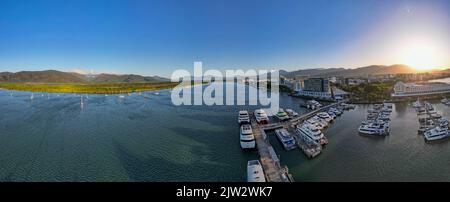 Aerial sunset panorama of boat marina, cityscape, rainforrest and mountains Stock Photo