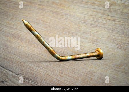 Rusty old bent metal nail on the floor, illustration. Old nails and other dirty objects are potential sources of tetanus bacteria. Stock Photo