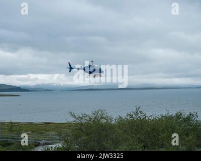 Staloluokta, Norrbotten, Sweden, Agust 11, 2021: Blue Fiskeflyg helicopter with tourist and supplies landing at sami village Staloluokta at Virihaure Stock Photo