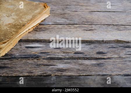 Old battered and yellowed book on wooden background Stock Photo