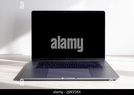 Front view of Modern laptop with empty black screen on minimalist desk. Template Mock up Stock Photo