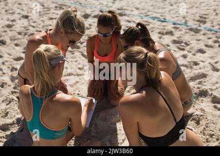 Female volleyball coach discussing with female players on the beach Stock Photo