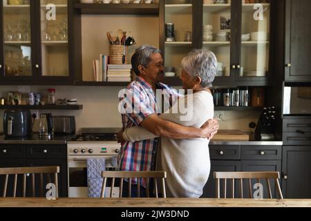 Senior african american couple standing and hugging in a kitchen Stock Photo
