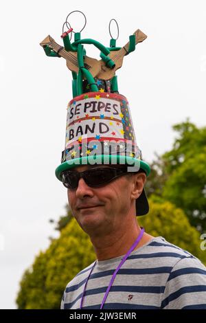 Bridport, Dorset UK. 3rd September 2022. A variety of style and quirky hats made and worn by humans and dogs at the Bridport Hat Festival in Dorset. Man wearing Hosepipe Band hat after ban introduced for hose pipes following dry drought. Credit: Carolyn Jenkins/Alamy Live News Stock Photo