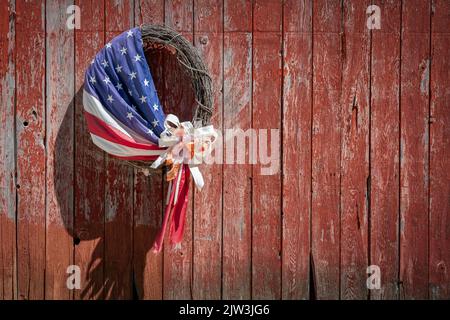 An American flag wrapped around a wreath made of sticks hangs on the side of a barn near Manitowoc, Wisconsin. Stock Photo