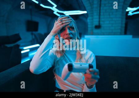 Blonde cyber gamer on console. The emotion of defeat. Stock Photo