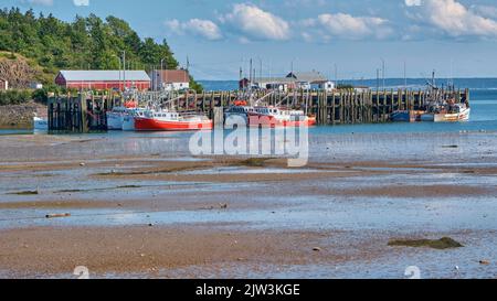 Fishing boats moored at the wharf in Candy Cove Nova Scotia at low tide. Stock Photo