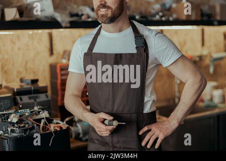 Unrecognizable repairman with a screwdriver standing on own workshop with coffee machines Stock Photo