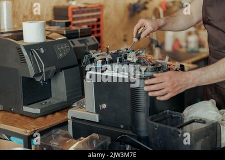 Close up of man hands repairing coffee machine in a workshop Stock Photo