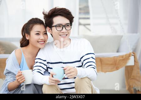Cheerful young Vietnamese couple enjoying morning coffee together Stock Photo