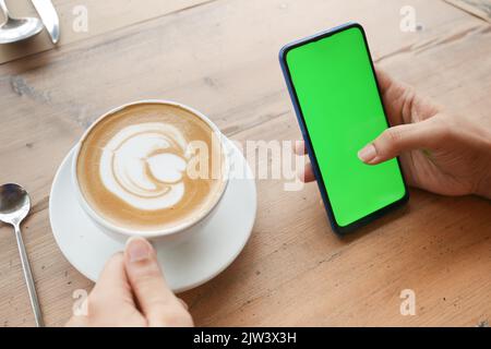 holding a cpu of coffee and using smart phone with green screen  Stock Photo