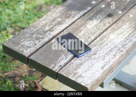 forget smartphone on a park bench, lost smart phone  Stock Photo