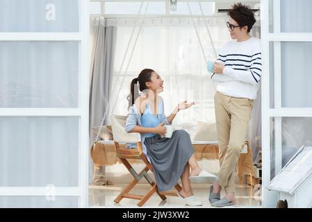 Cheerful young Asian couple discussing latest news Stock Photo