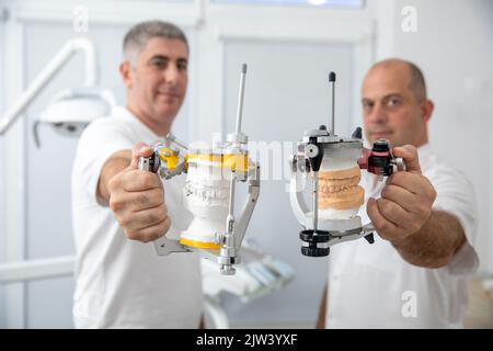Two male dentists holding dental articulators in dental clinic Stock Photo