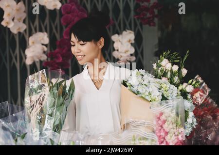 Lovely smiling Vietnamee young woman with many bouquets Stock Photo