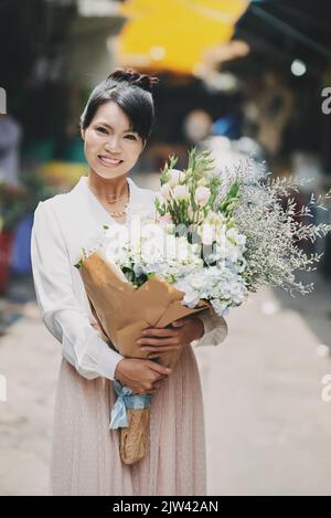 Attractive Vietnamese woman with big bouquets smiling and looking at camera Stock Photo