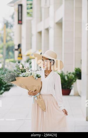 Attractive young woman in summer hat holding a big bouquet Stock Photo
