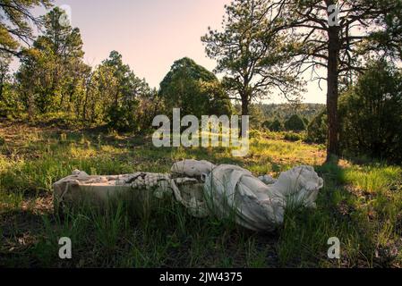 A fallen marble statue of a woman holding foods that represent harvest, lying on it’s back. Stock Photo